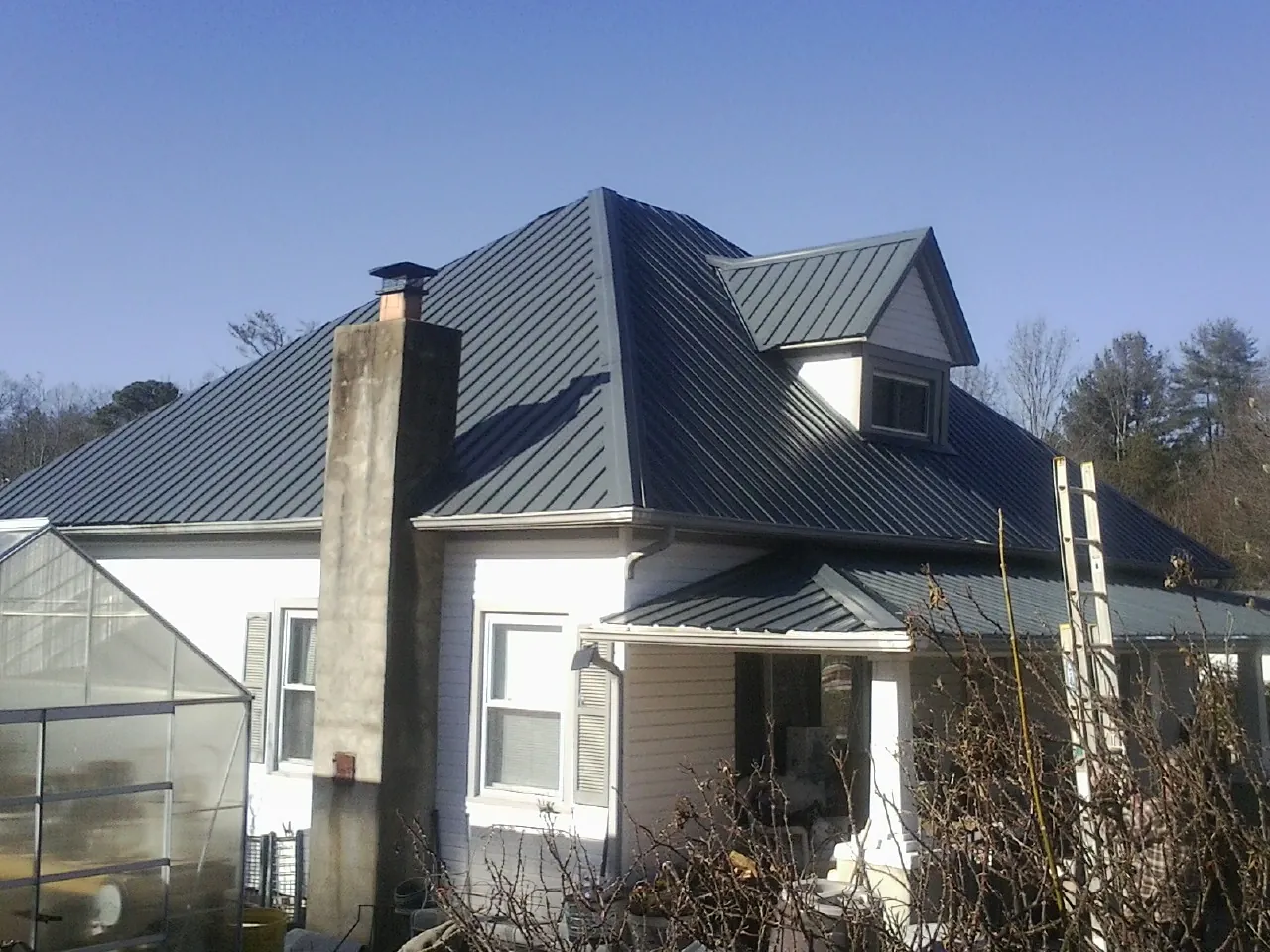 Dark blue standing seam metal roof on a white farmhouse with dormer — Slate & Tile Roof Repair by Roofing Brothers in Sunnyside