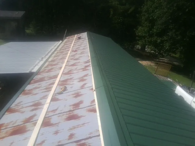 Old rusted panels beside newly installed green metal roofing — Wind Damage Roof Repair by Roofing Brothers in Sunnyside