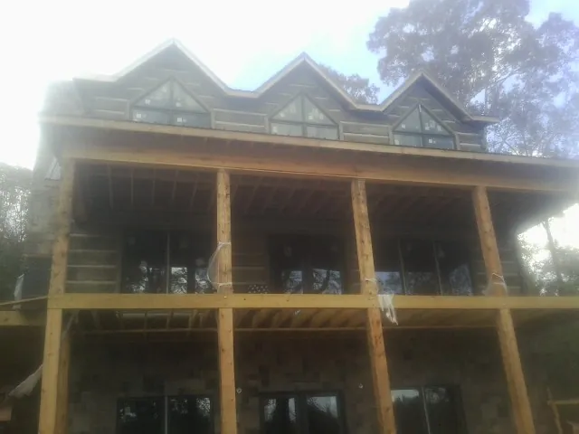 Dormers and porch framing on a large log home under construction — Roof Coating work by our crew in Sunnyside