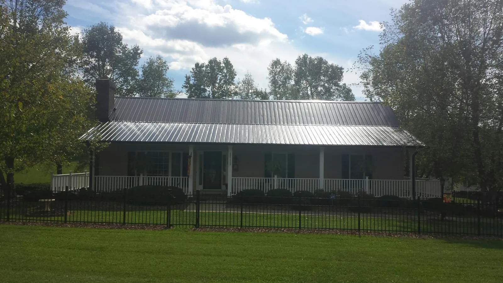 Gray metal roof on a brick ranch with a full width front porch — Gutter Guard Installation work by our crew in Sunnyside